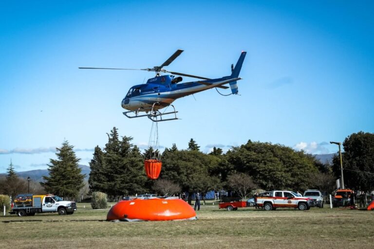 Helicóptero Airbus H-125 con bambi bucket sobrevolando un lago en Córdoba