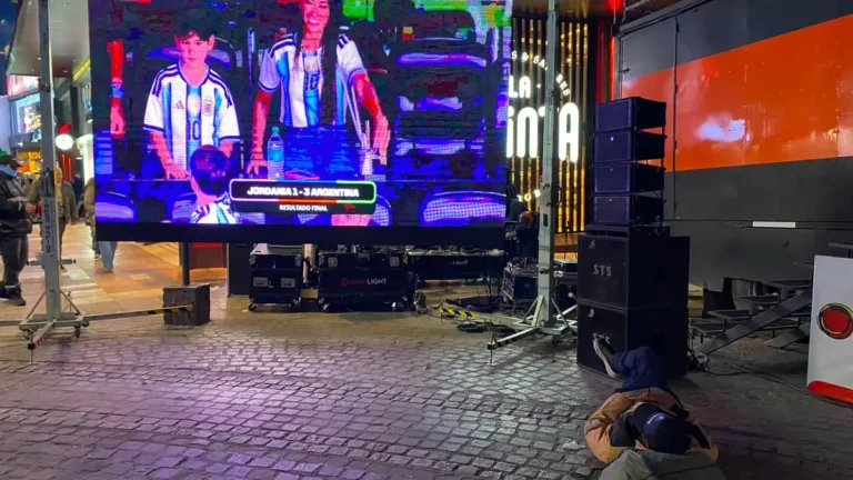 Hincha acostado en la peatonal de Villa Carlos Paz frente a pantalla gigante con resultado del partido Argentina vs Jordania