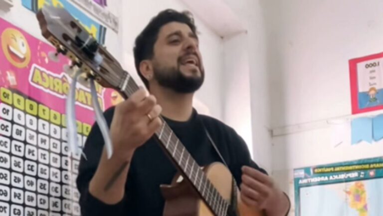 Profesor Gonzalo Morales tocando la guitarra frente a sus alumnos en el aula