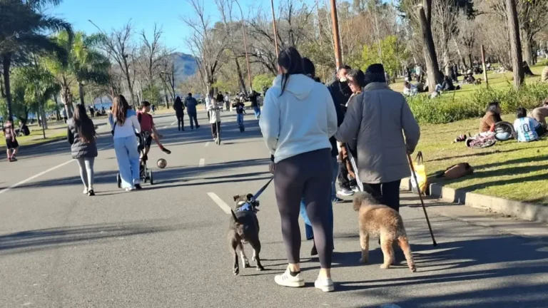 Costanera del lago San Roque en Villa Carlos Paz con personas caminando y bicicletas durante un domingo soleado de invierno